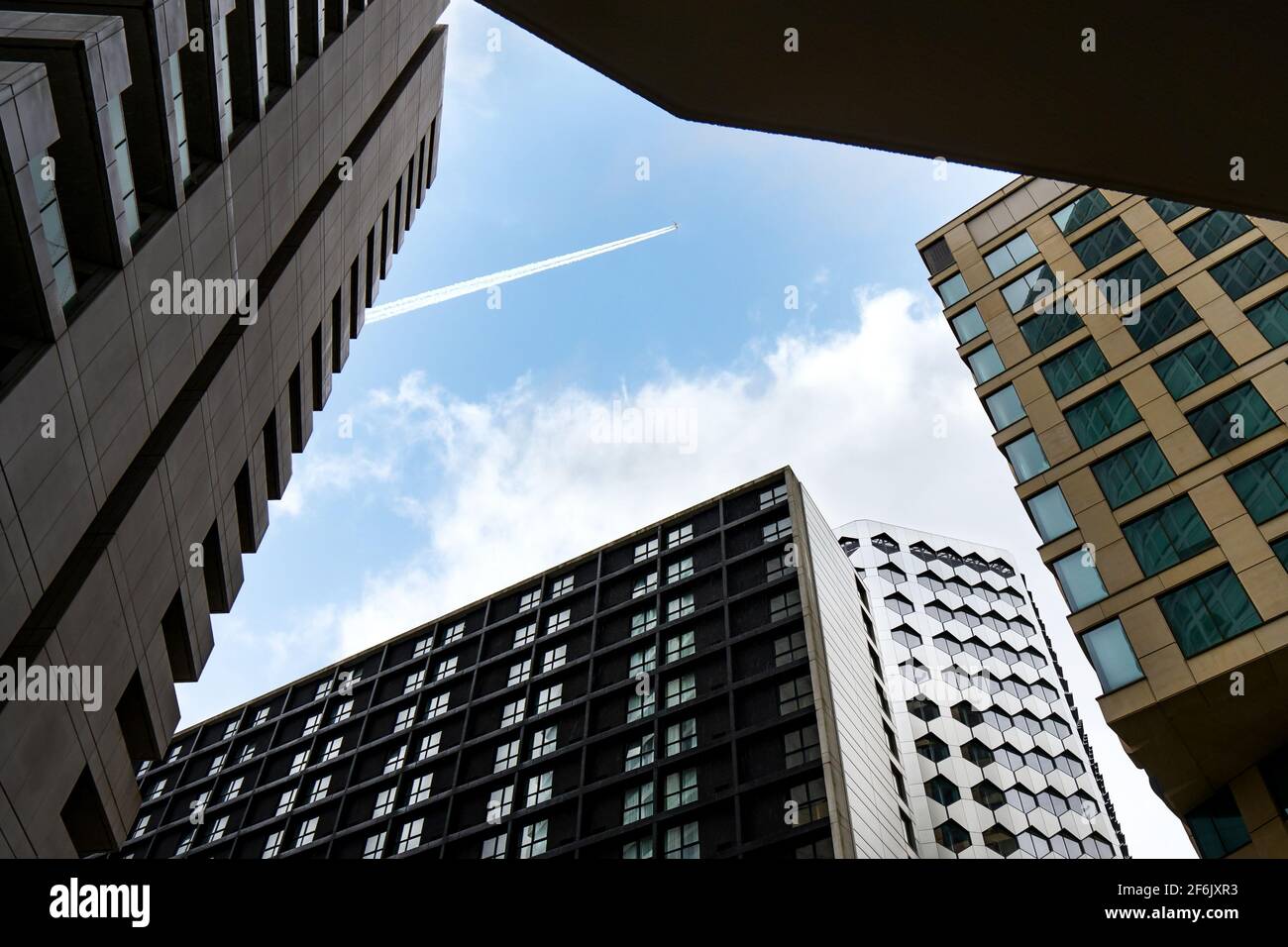 Birmingham England 3.2.2020 - Blick durch den Wolkenkratzer-Büroturm Block am Flugzeug Jumbo Jet fliegen über Trails in der Blauer Himmel, niedriger Winkel Stockfoto