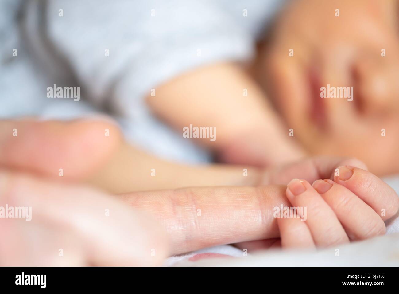 Nahaufnahme eines neugeborenen Jungen, der den Finger des Elternteils hält Stockfoto