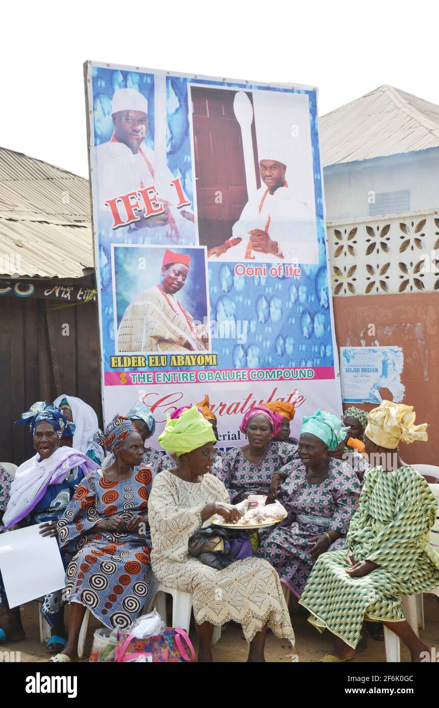 Frauen aus dem Königshaus Giesi sitzen während der Krönungszeremonie von Oba Adeyeye Enitan Ogunwusi, Ojaja II. Vor Ooni von Ifes Porträtbanner Stockfoto