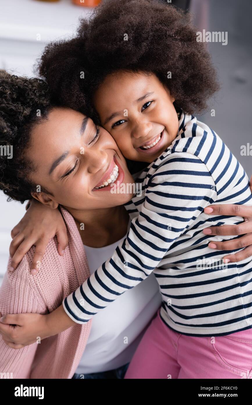 Fröhliche afroamerikanische Mutter und Tochter umarmen zu Hause Stockfoto