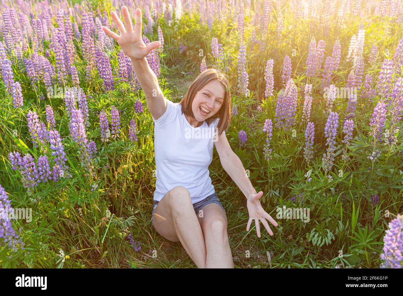 Glückliches Mädchen lächelt im Freien. Schöne junge Brunete Frau ruht auf Sommerfeld mit blühenden wilden Blumen grünen Hintergrund. Freies glückliches europäisches Wom Stockfoto