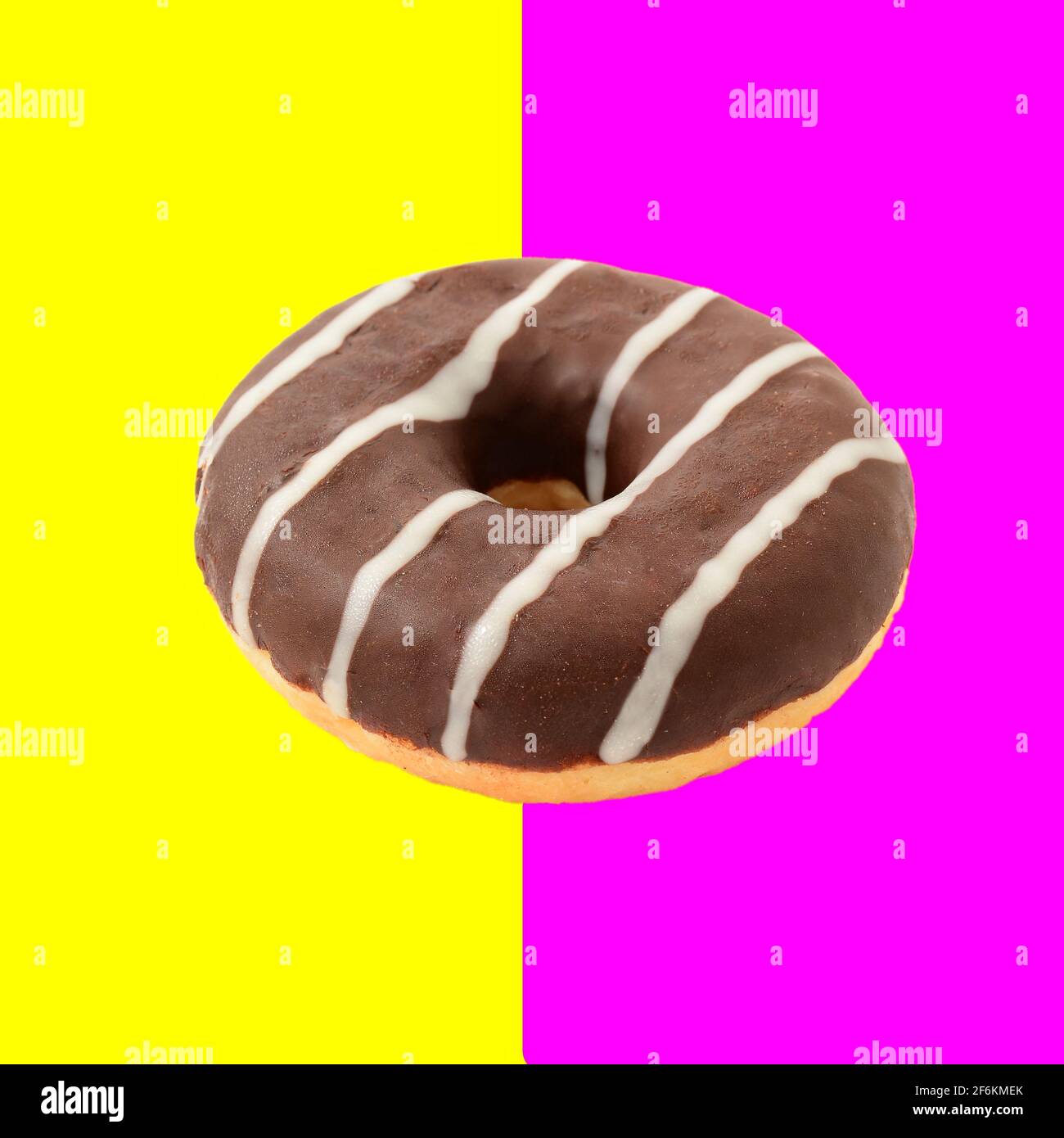 Ein ganzer Schokoladen-Donut isoliert auf halbrosa und halbgelben Hintergrund, Retro-Vintage-Stil Bild. Stockfoto