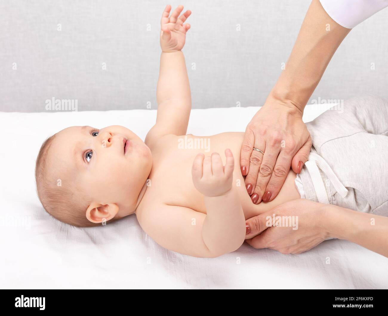Weibliche Kinderarzt oder Arzt untersucht das Baby Bauch. Arzt Durchführen manueller Palpation. Kind körperliche Untersuchung Konzept Stockfoto