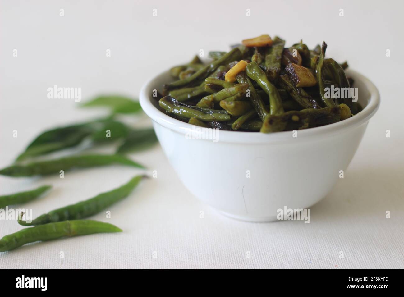 Frittierte Bohnen mit gehackter Kokosnuss, grünen Chilis, Kurkuma und Curryblättern mit Kokosöl umrühren. Ein Gradient von Kerala-Mahlzeit Stockfoto