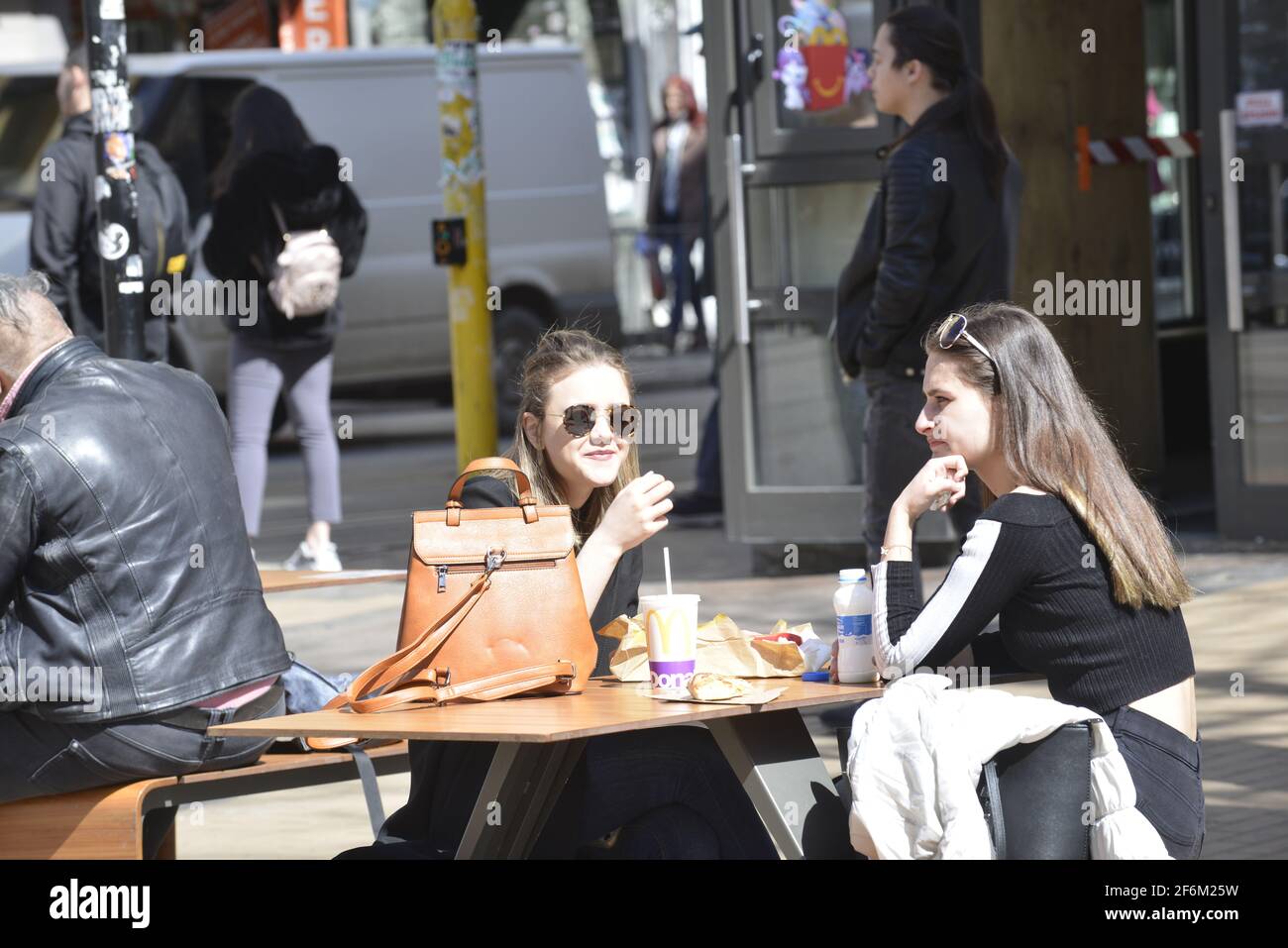 Sofia, Bulgarien - 1. April 2021: Zwei Mädchen, die draußen essen, genießen die Leichtigkeit der Einschränkungen Stockfoto