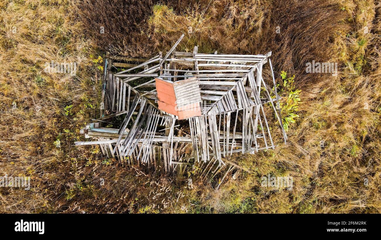 Draufsicht auf das Dielendach eines zerstörten Hauses. Ein verlassene Holzgebäude steht allein auf einem leeren Grundstück. Foto von Ruinen, die Sehnsucht und Traurigkeit hervorrufen. Stockfoto