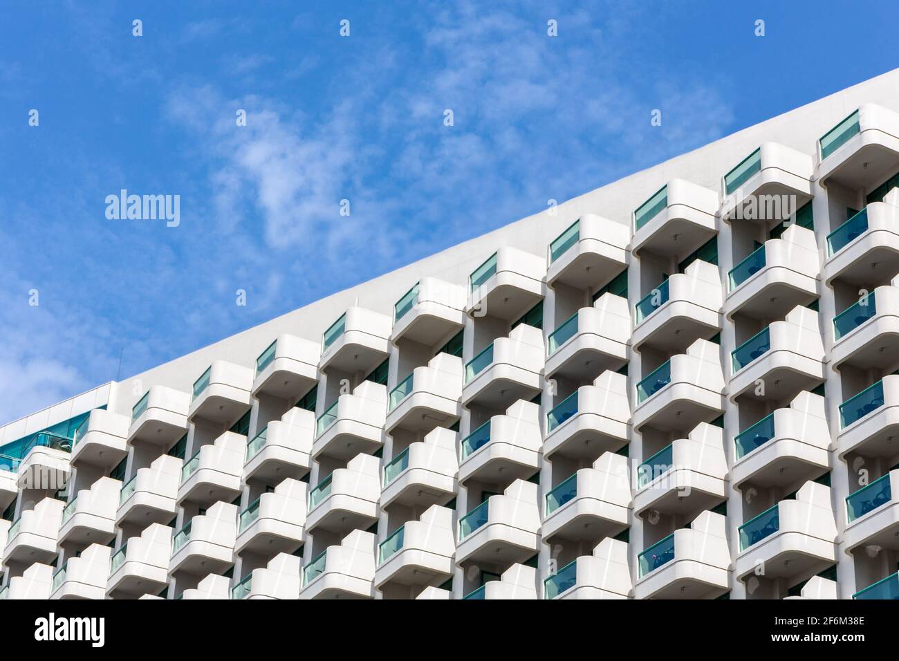Reihen und Muster von identischen kleinen Balkonen eines modernen Luxushotels in Dubai, die geometrische Muster bilden, mit blauem Himmel im Hintergrund, diagonal Stockfoto