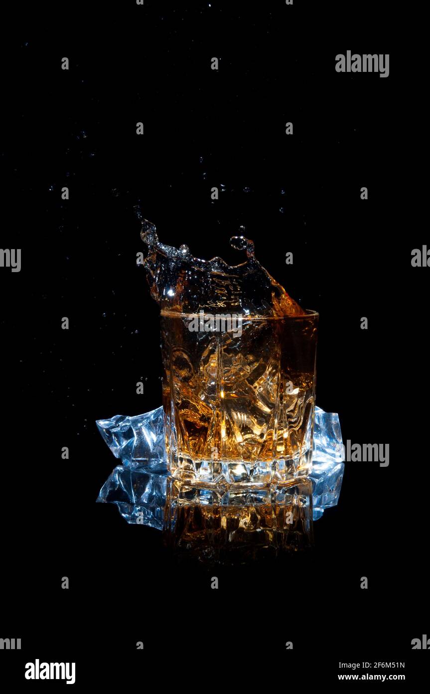 Whiskey mit Spritzer isoliert auf schwarzem Hintergrund. Scotch mit Eis in einem Glas. Stockfoto
