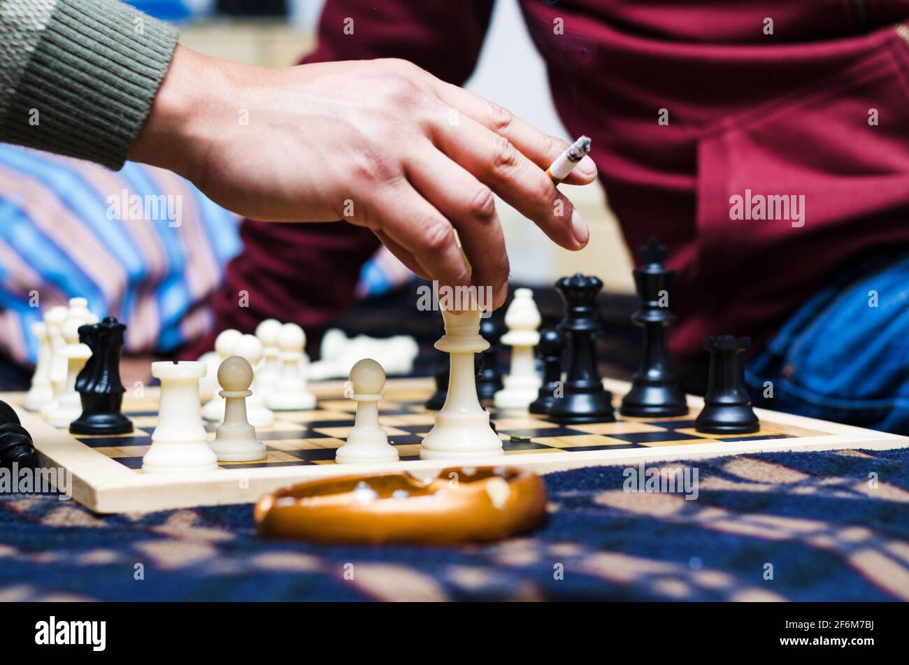 Zigarre auf einem Aschenbecher mit dem Hintergrund einer Schachpartie. Stockfoto