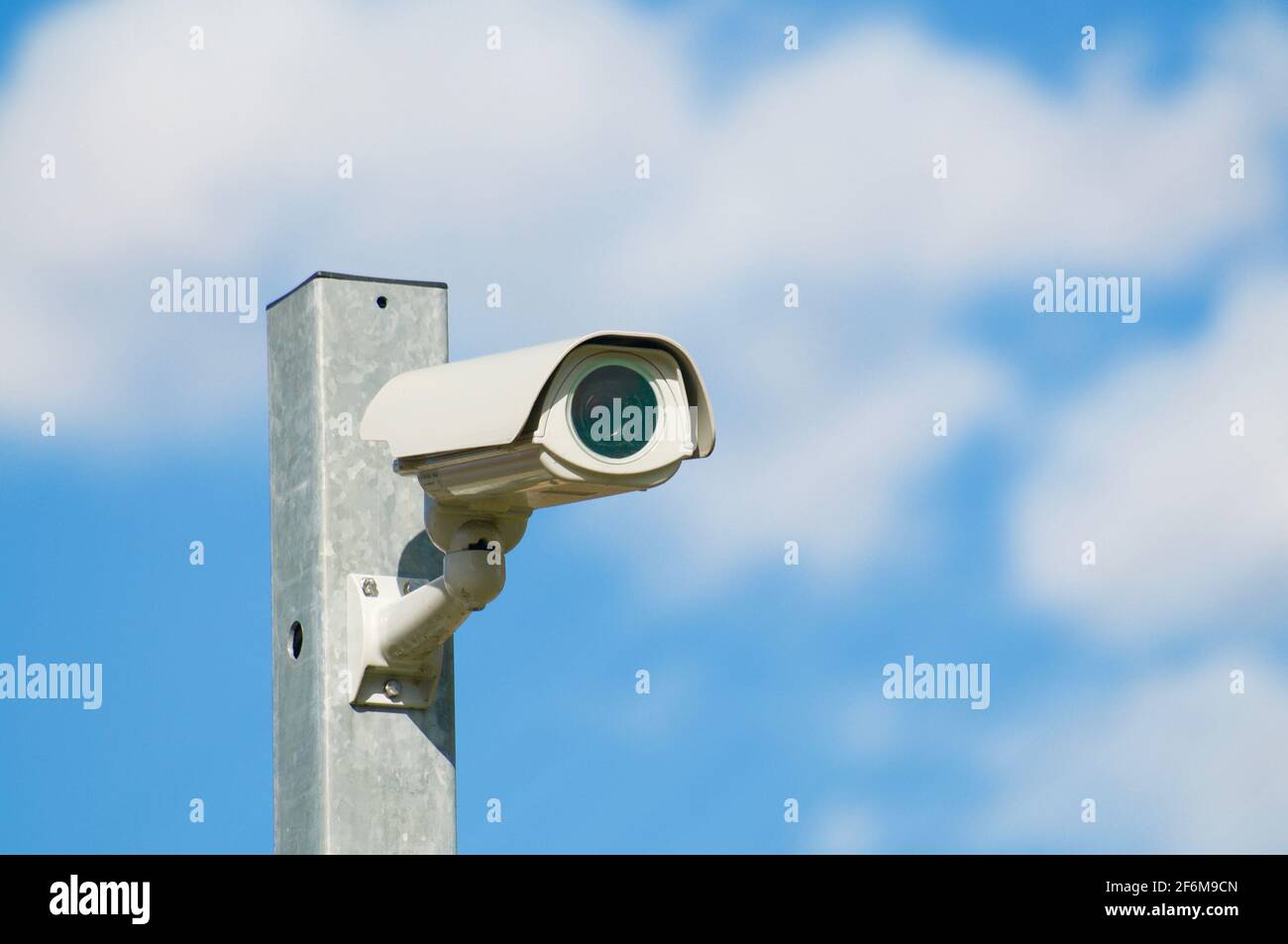 CCTV-Überwachungskamera, die auf einem Eisenmast mit blauem Himmel und Wolken im Hintergrund installiert ist und sich in Lugano, Schweiz, befindet Stockfoto