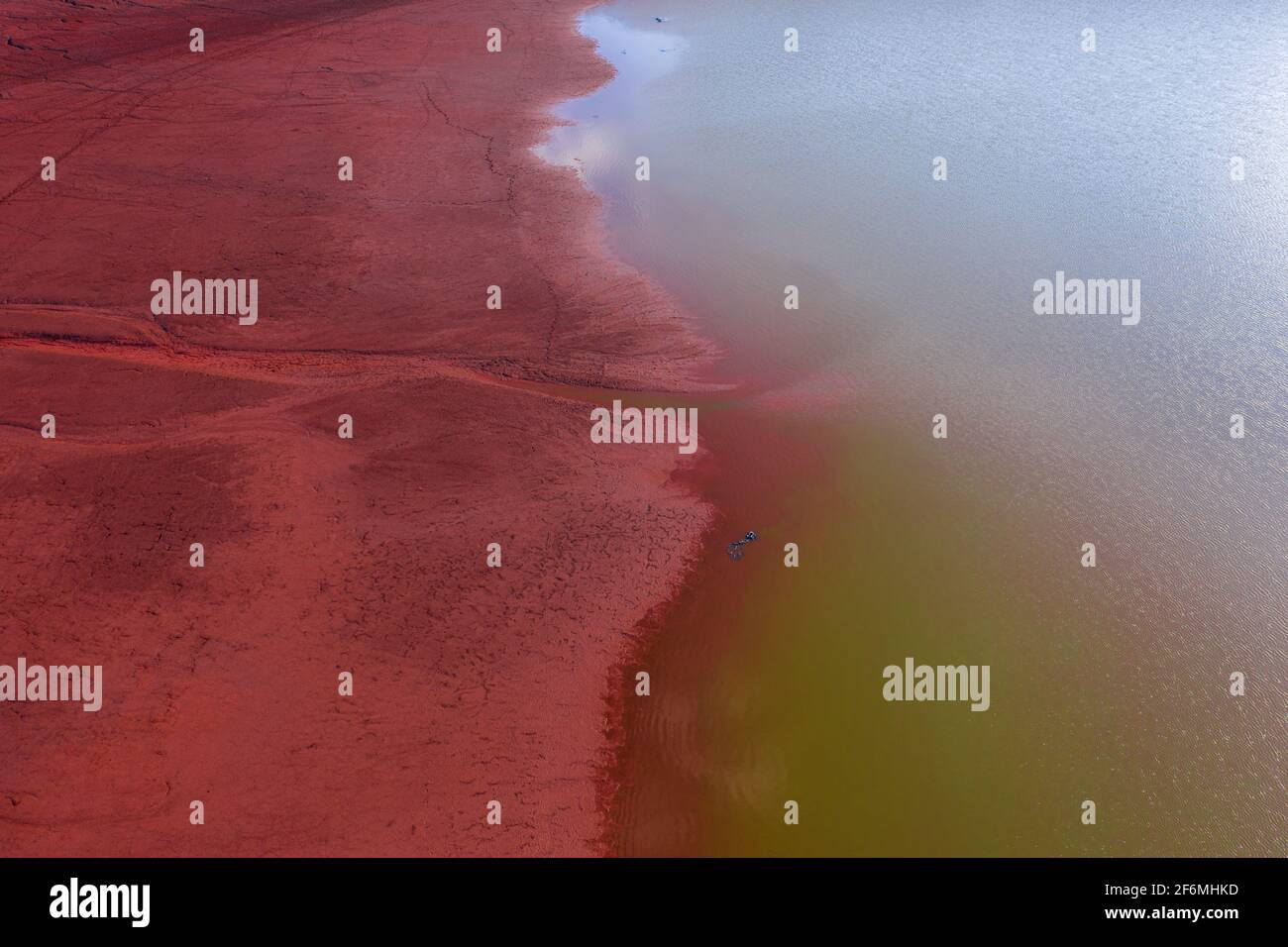 Neszmély, Ungarn - Luftaufnahme der trockenen roten Schlammoberfläche mit grünem See. Stockfoto