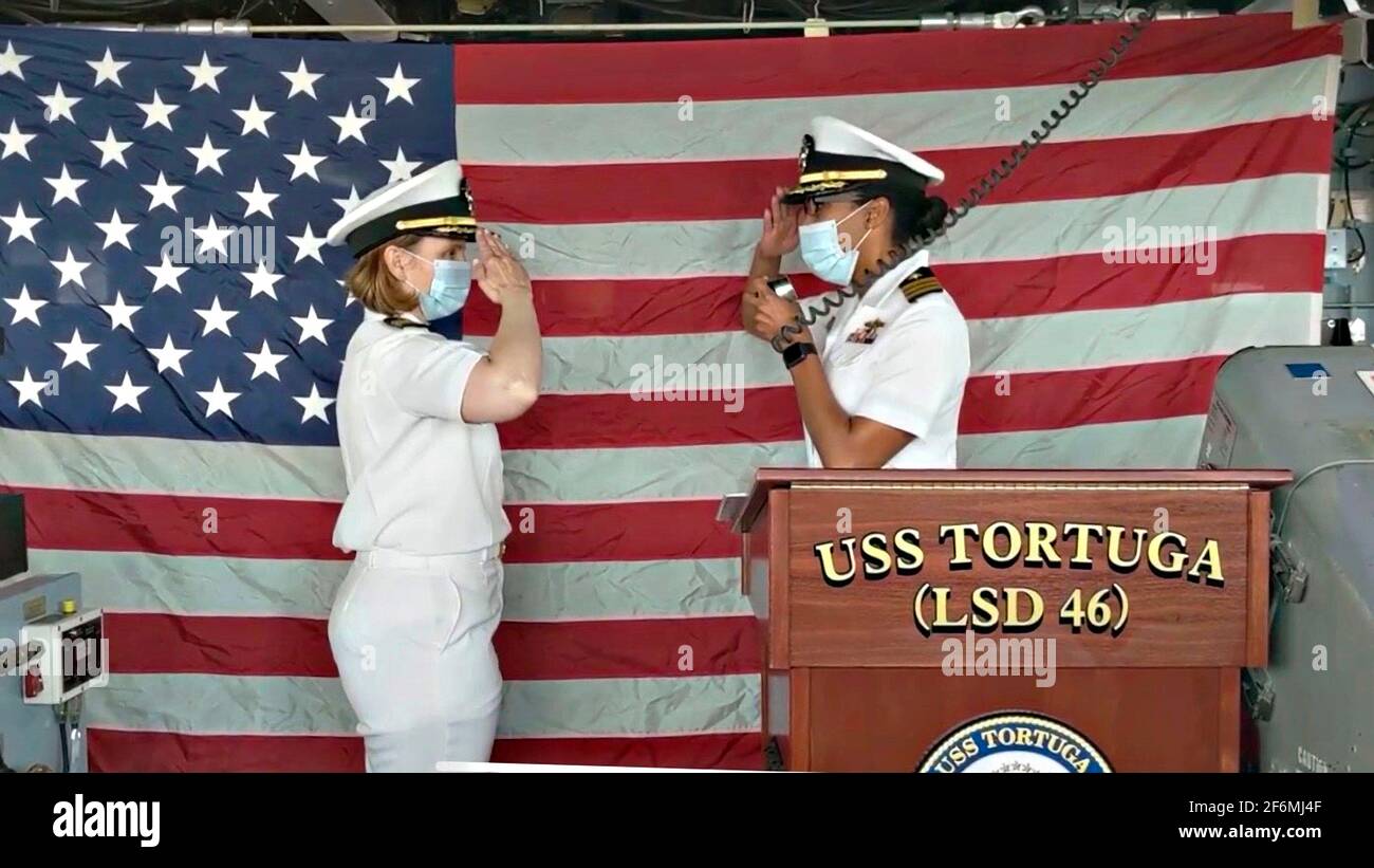 US Navy Cmdr. Kimberly Jones, der neue Kommandant des Docks der Whidbey Island-Klasse USS Tortuga, begrüßt den scheidenden Cmdr. Rosie Goscinski während der Befehlswechselzeremonie am 16. Juli 2020 in Virginia Beach, Virginia. Stockfoto