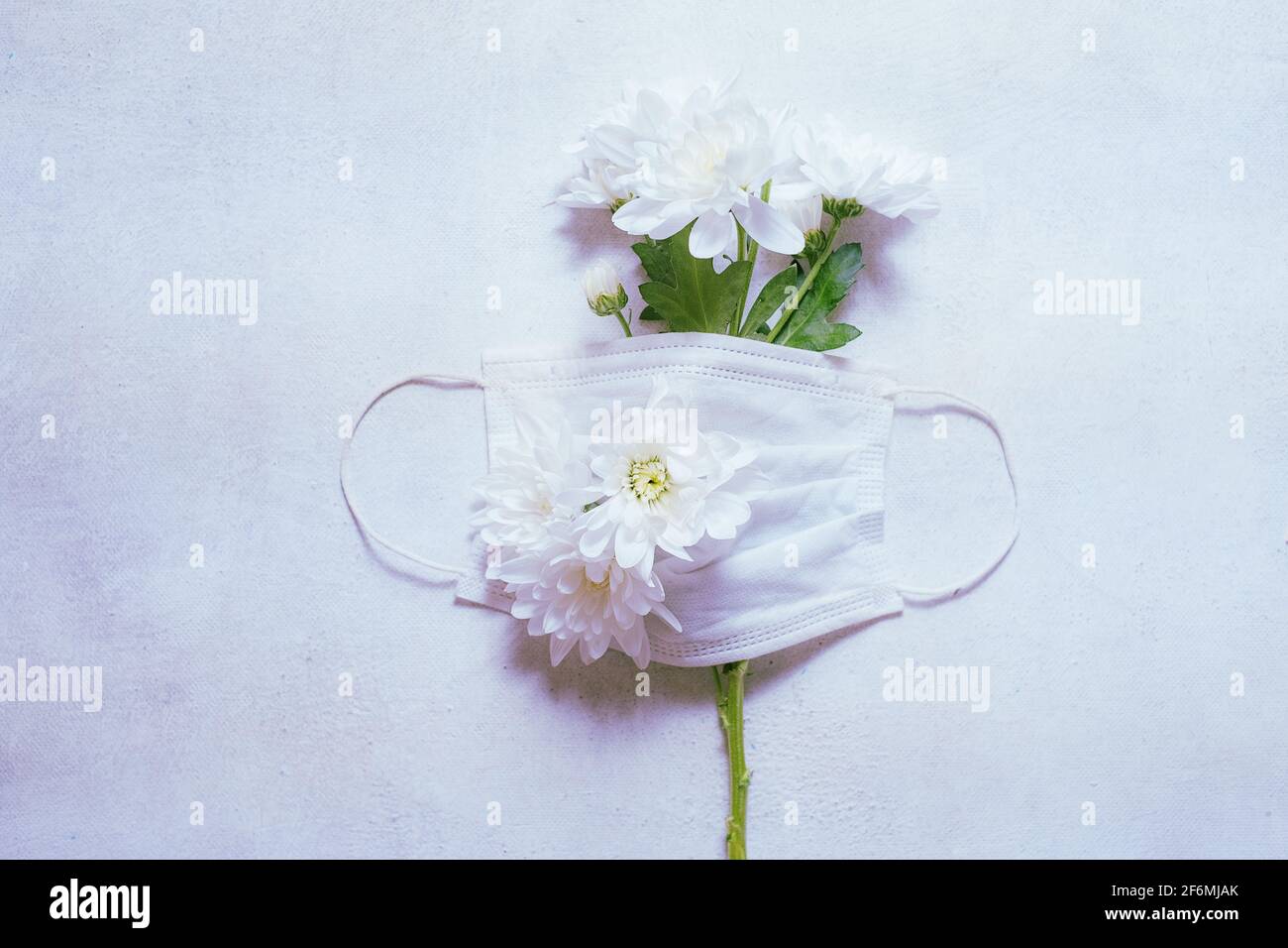 Medizinische Konzept Maske und ein Zweig von Frühlingsblumen Symbol der Hoffnung. Stockfoto