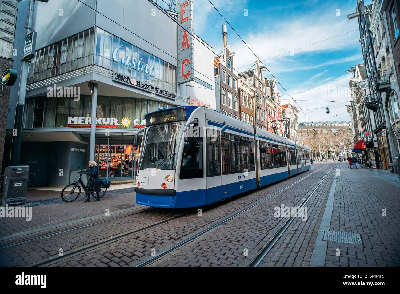 Amsterdam, Niederlande - März 2020: Straßenbahn in der Innenstadt von Amsterdam, Straßenszene aus dem historischen Zentrum mit öffentlichen Verkehrsmitteln, Menschen und alte Architektur mit Geschäften oder Geschäften. Stockfoto