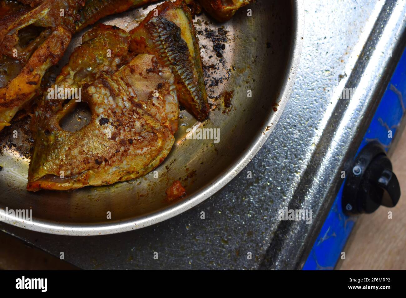 Überhängender Schuss verschiedener Fischstücke, die auf einer Pfanne mit Öl darin braten. Es wird in indischem Stil gekocht, der in Kerala und Südindien gefunden wird. Stockfoto Überhängender Schuss verschiedener Fischstücke, die auf einer Pfanne mit Öl darin braten. Es wird in indischem Stil gekocht, der in Kerala und Südindien gefunden wird. Stockfoto