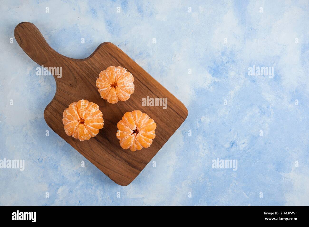Drei frisch geschälte Mandarinen auf Holzschneidebrett Stockfoto