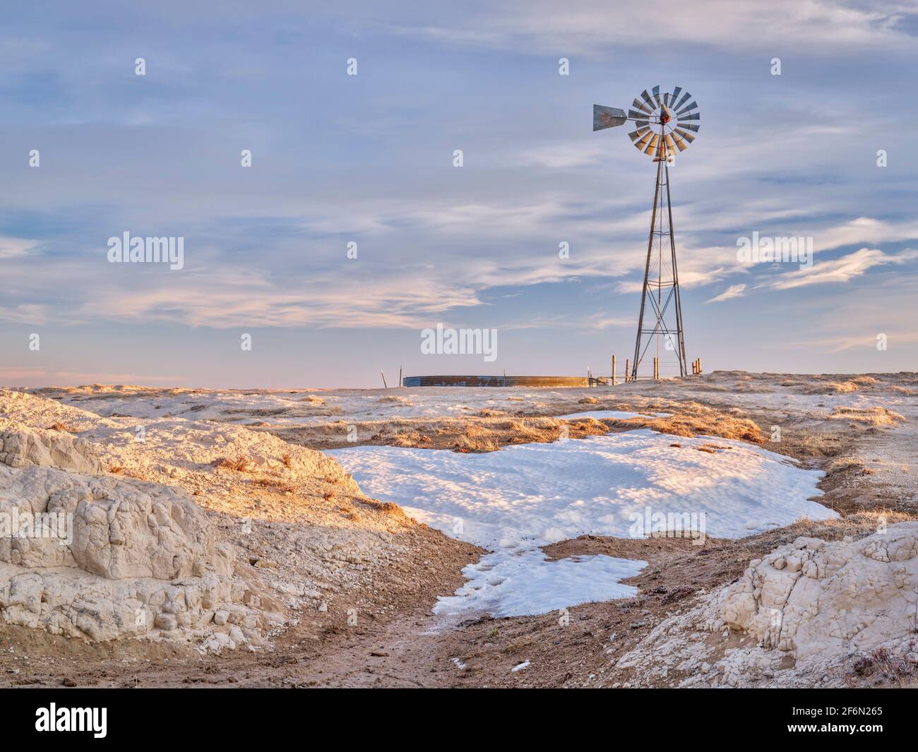 Windmühle mit Pumpe und Viehwassertank in Shortgrass-Prärie, Pawnee National Grassland im Norden Colorados, Winter- oder Frühfrühlingslandschaft Stockfoto