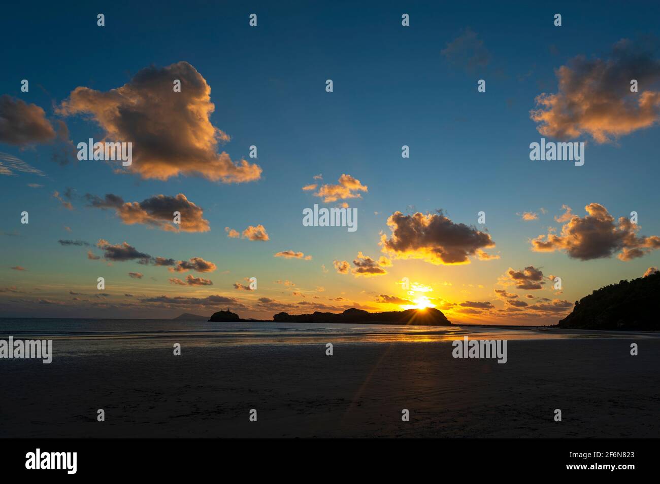 Stimmungsvoller Blick auf die Sonne am Horizont bei Sonnenaufgang am Strand, Cape Hillsborough, Queensland, QLD, Australien Stockfoto