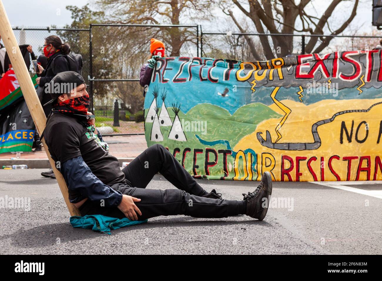Washington, DC, USA, 1. April 2021. Im Bild: Danny Grassrope vom Graswurzelkollektiv Cheyenne Runs sitzt mit Fahrradschlössern an einem Stativ angekettet. Er und andere Mitglieder des Kollektivs hielten den Block der H Street NW zur Unterstützung indigener Jugendlicher ab und hielten eine Kundgebung ab und marschieren gegen die Dakota Access Pipeline und die Line 3 Pipeline vor dem Weißen Haus. Kredit: Allison C Bailey/Alamy Live Nachrichten Stockfoto