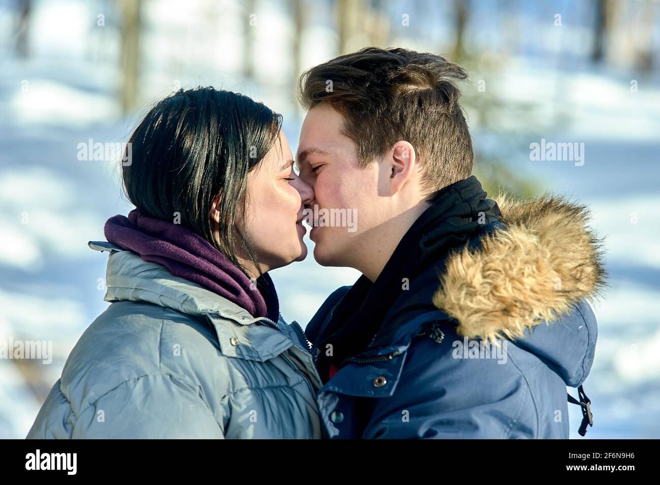 Junges Paar küsst sich im Freien in einem Winterpark aus nächster Nähe Stockfoto