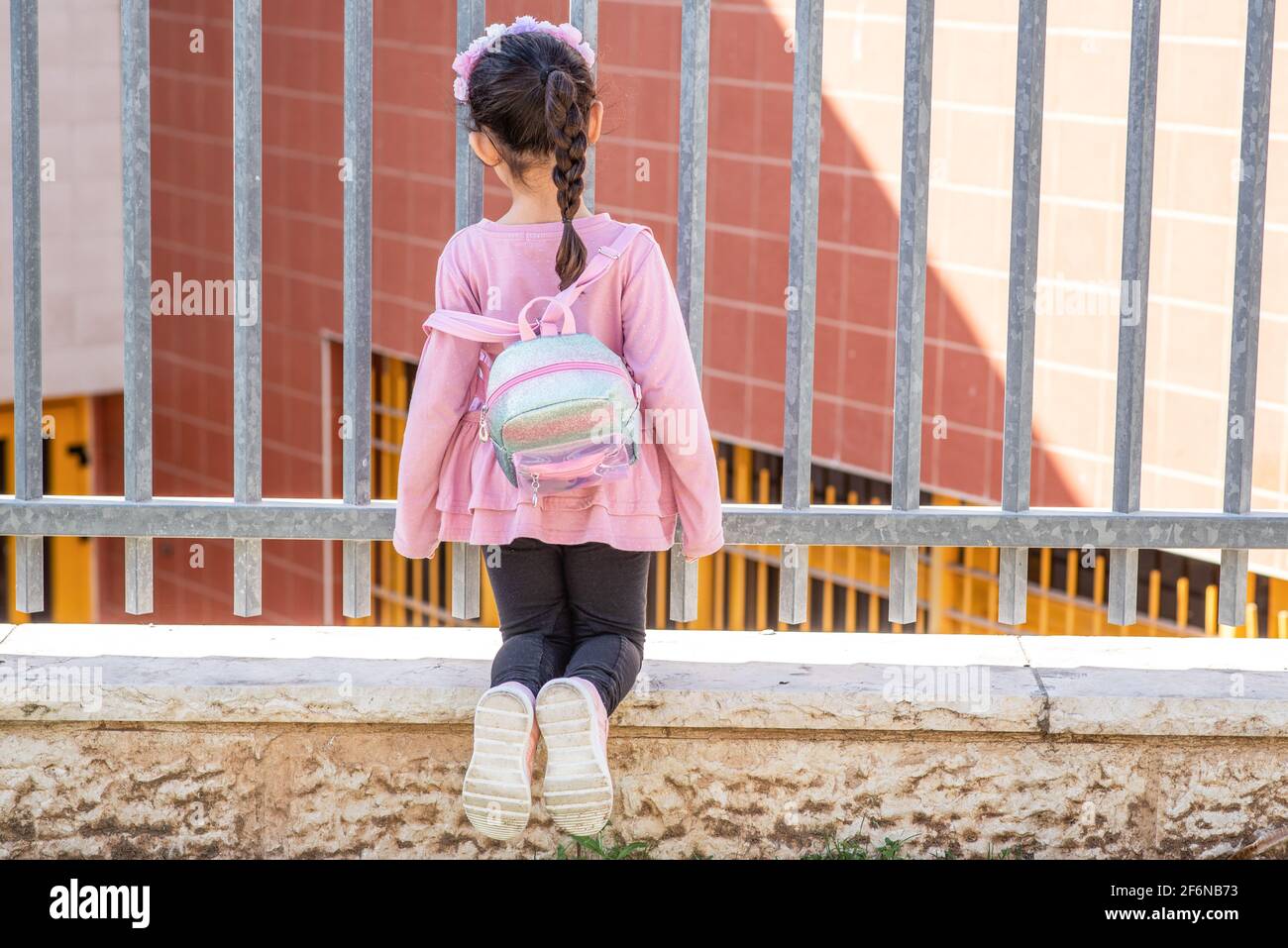 Kind mit Schulrucksack Blick auf Schulhof. Schulen und Vorschulen bleiben während der Aussperrung, der Coronavirus-Pandemie und der zweiten Welle von Covid-19 für Kinder geschlossen. Stockfoto