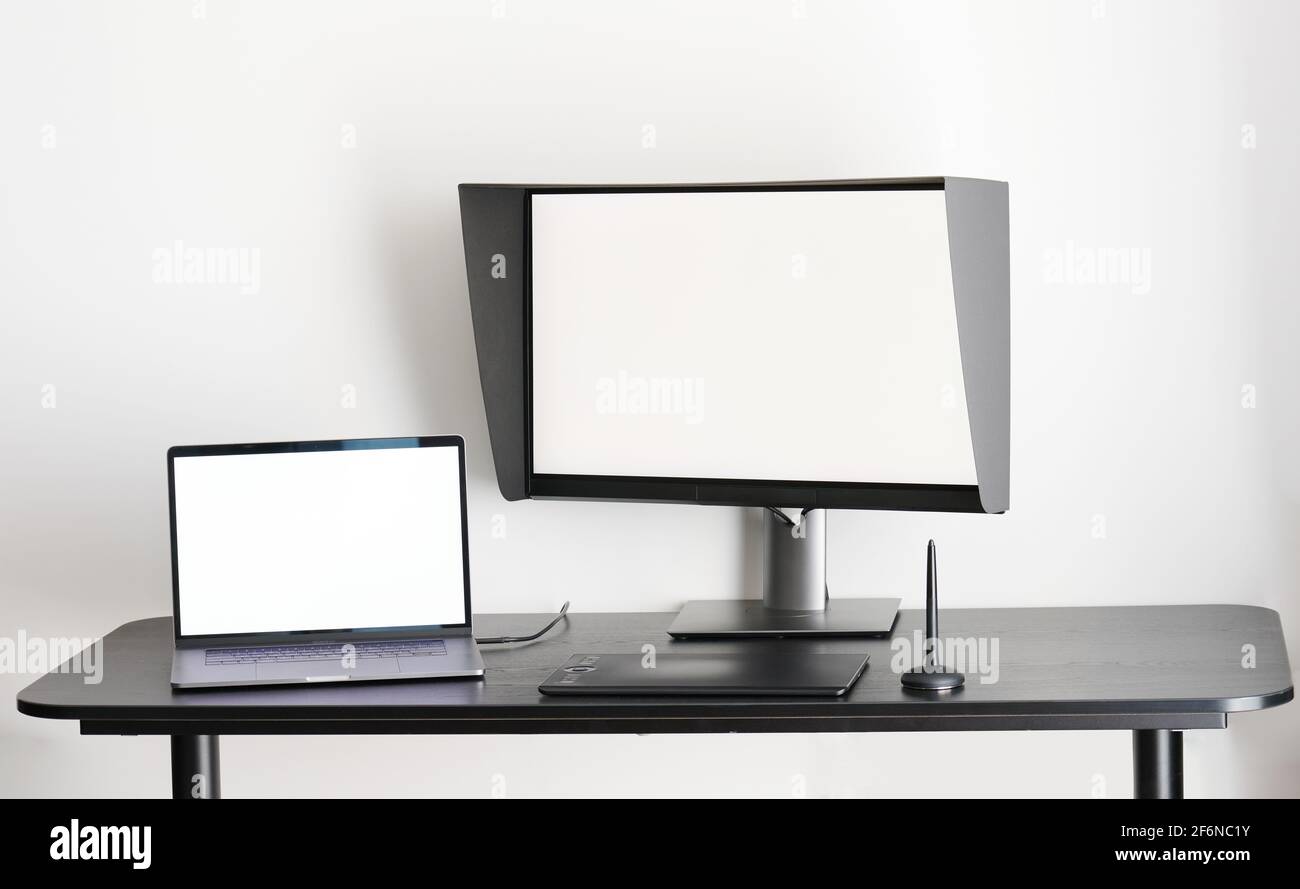 Arbeitsbereich des Grafikdesigners. Tisch mit Laptop und Monitor auf weißem Hintergrund isoliert Stockfoto
