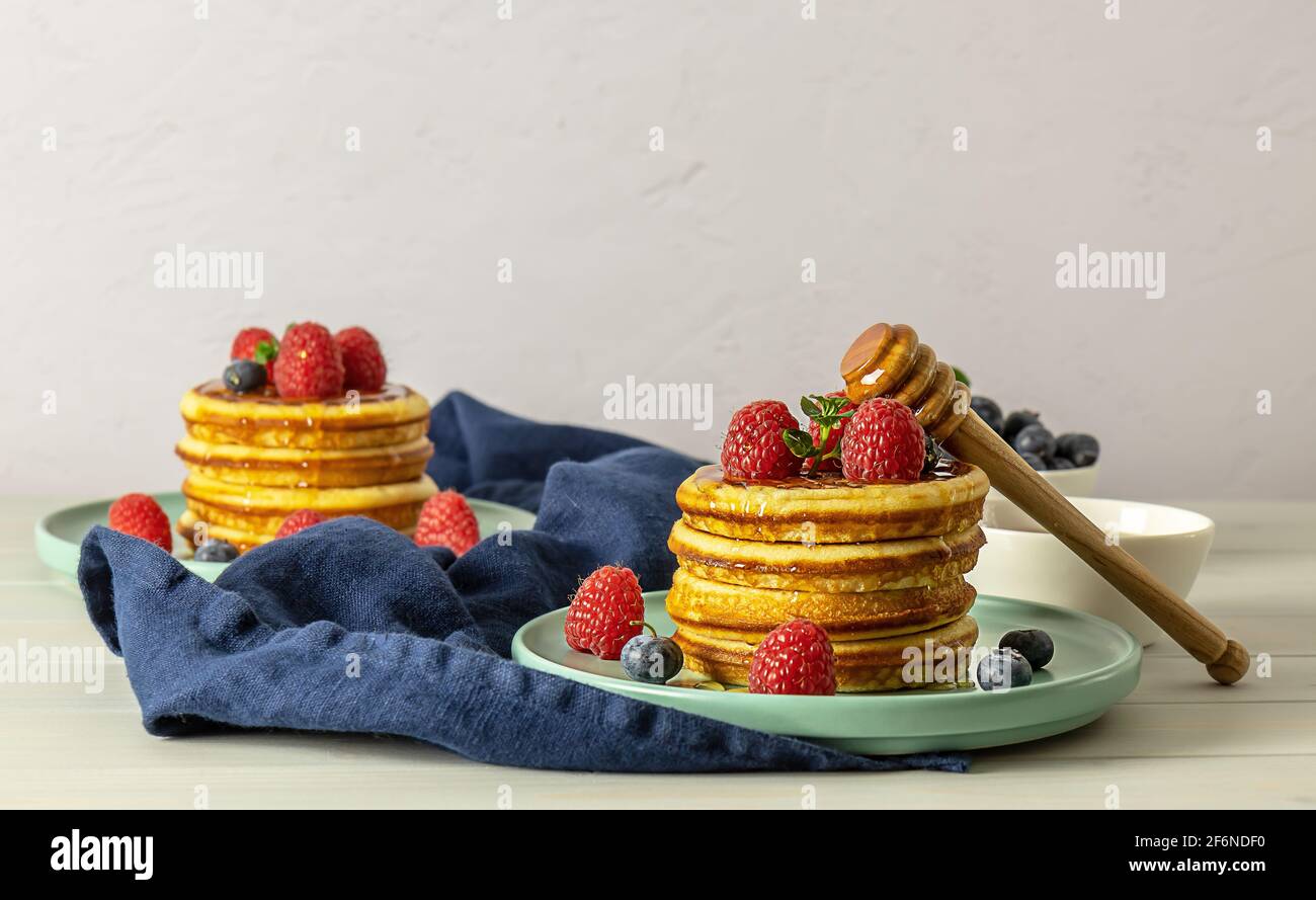 Leckere amerikanische Pfannkuchen mit Himbeeren, Heidelbeeren und Honig. Stockfoto