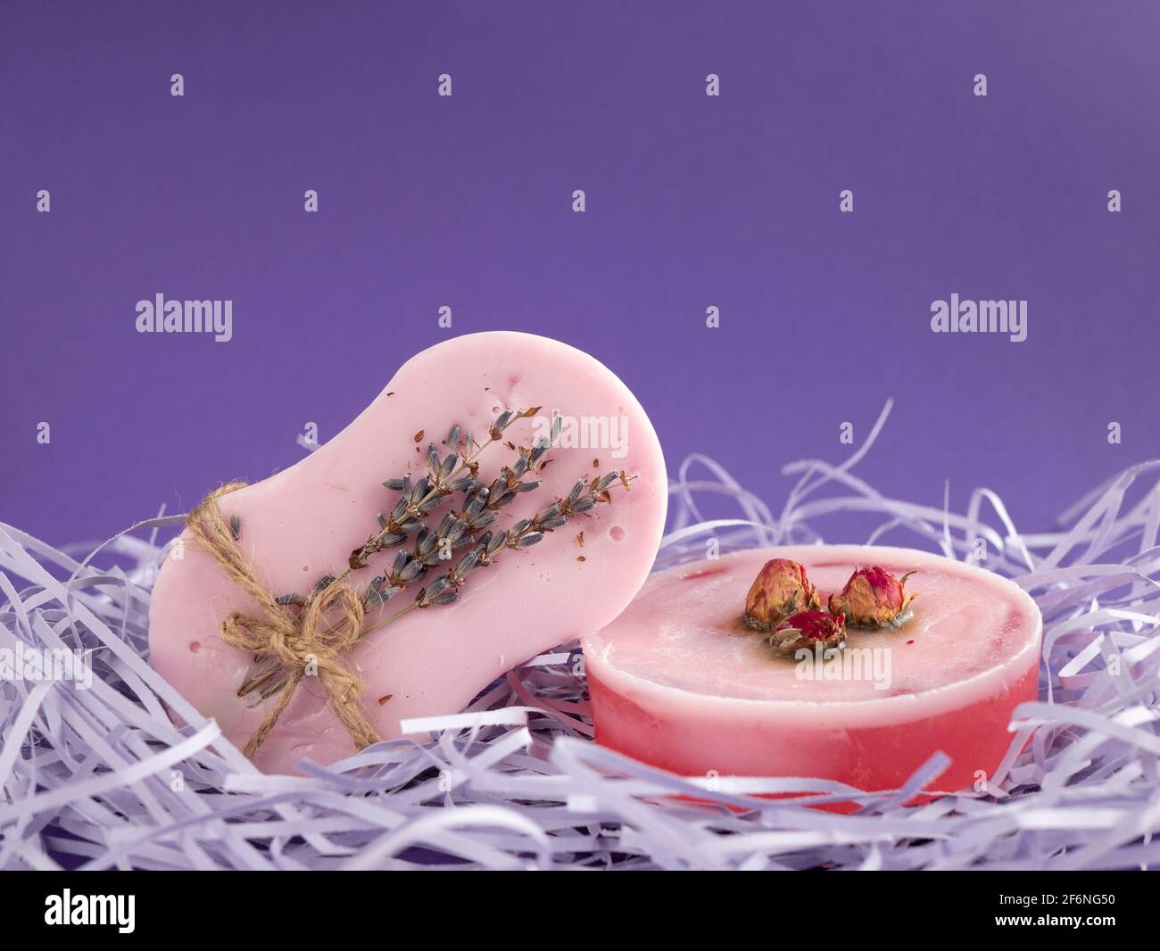 Natürliche Seifenstücke mit Rosen- und Lavendelaromen mit Platz für Kopien auf violettem Hintergrund. Spa- und Hautpflegeprodukte Stockfoto