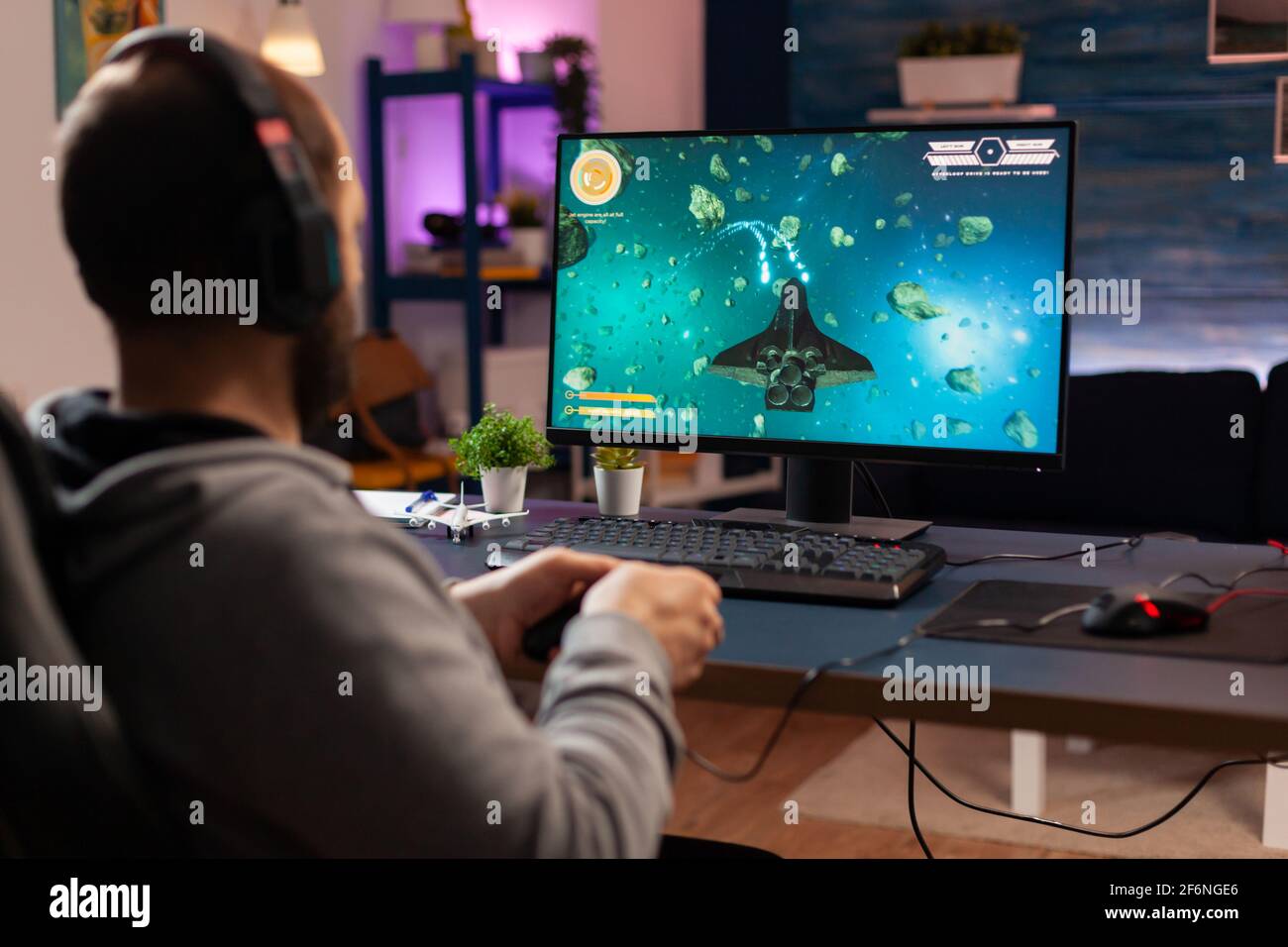 Gamer-Player mit Kopfhörern Durchführung Videospiel mit modernen Grafiken für Weltraum-Shooter-Meisterschaft. Online-Streaming von Cyber-Leistung während eines Gaming-Turniers mithilfe von Technologie-Netzwerk Wireless Stockfoto