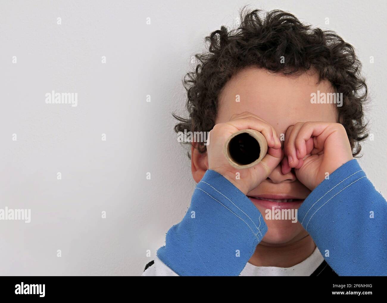 Junge Blick durch Fernglas Papierrolle auf weißem Hintergrund Stock Foto Stockfoto