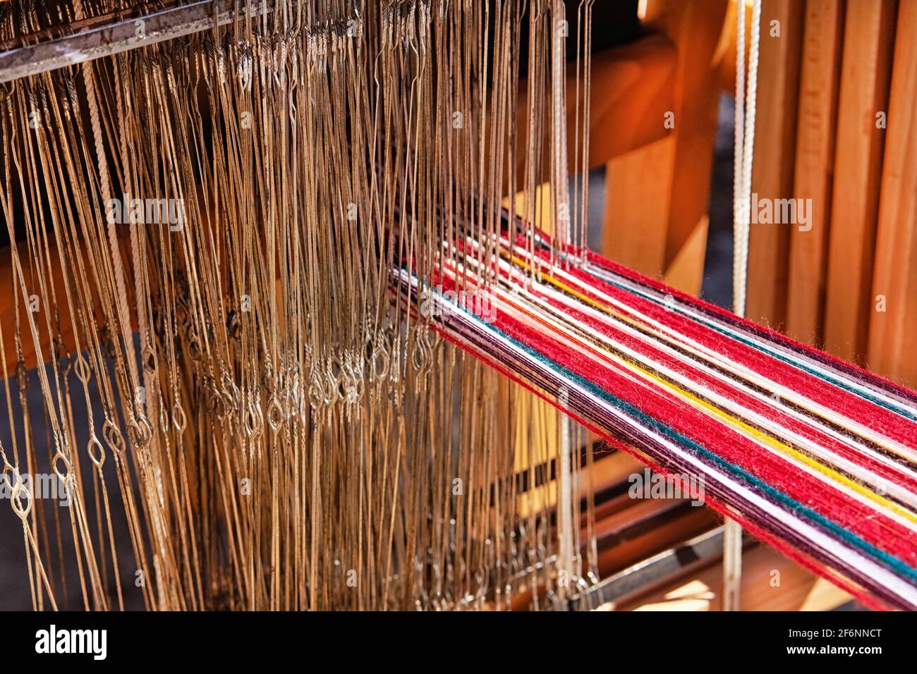 Die Strähne aus mehrfarbiger Wolle sind auf dem traditionellen Webstuhl eingefädelt. Nationales Weberei Handwerk Konzept. Stockfoto