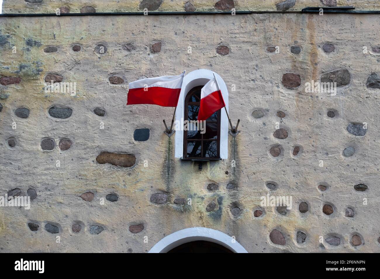Die polnische Nationalflagge winkt gegen die Steinmauer. Weiches Licht, an einem bewölkten Tag. Stockfoto