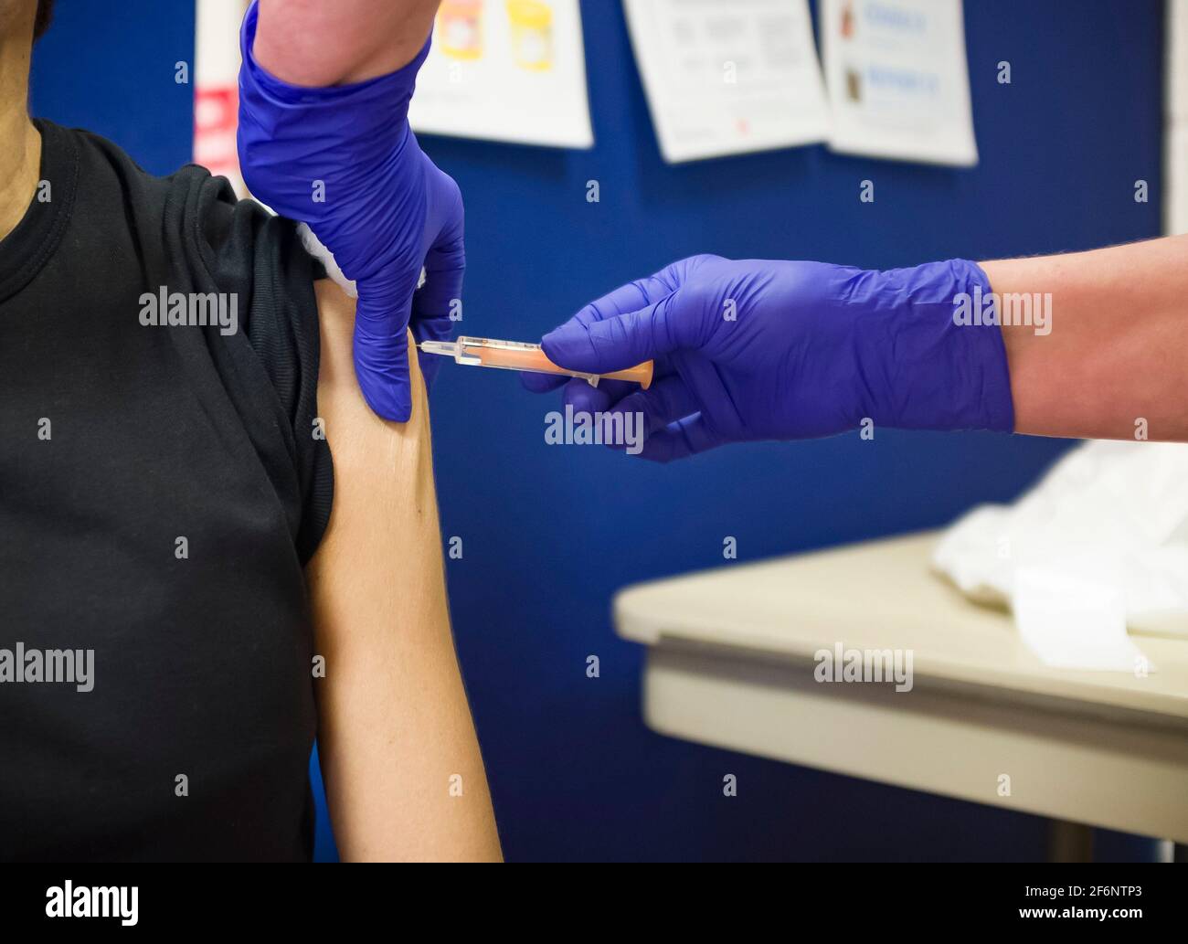 Nahaufnahme einer britisch-asiatischen Frau, die eine Injektion mit Arm, Grippe, Influenza- oder Covid-19-Impfstoff erhält, Großbritannien Stockfoto