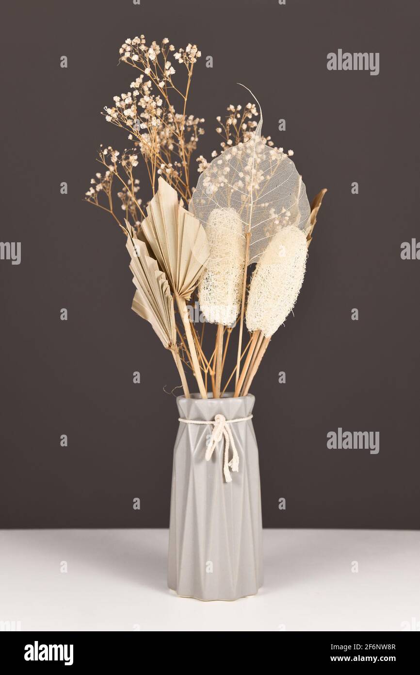 Getrocknete natürliche Blumen Bouquet in grauer Vase mit Blumen und Blättern wie Palmblatt, Skelett Blatt, Luffa und gemeinsame Gypsophila Blumen Stockfoto