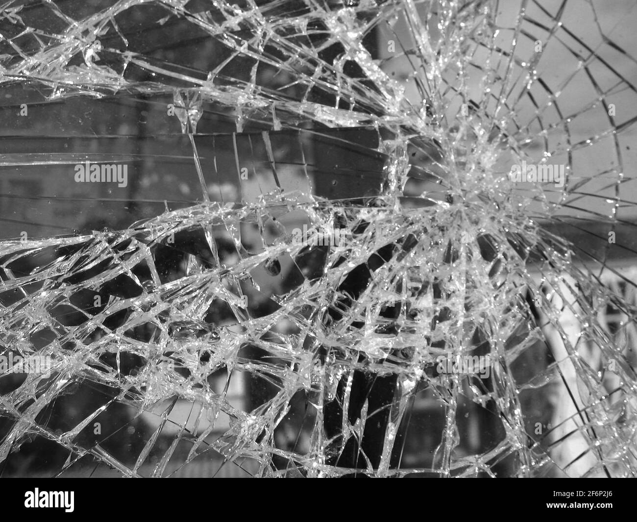 Schwarz-Weiß-Foto von gebrochenem Glas, radiales Muster mit Rissen Stockfoto