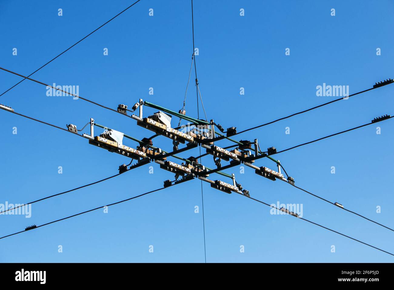 Elektrische Übertragungsleitungen über dem Kopf vor blauem Himmel. Industrielle elektrische Kabelleitungen, die vor dem klaren Himmel über dem Kopf verlaufen. Stockfoto