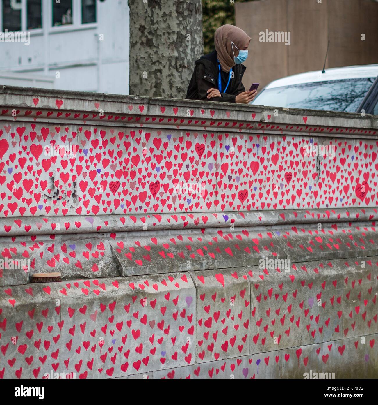 Eine maskierte NHS-Mitarbeiterin über der National Covid Memorial Wall in London. Stockfoto