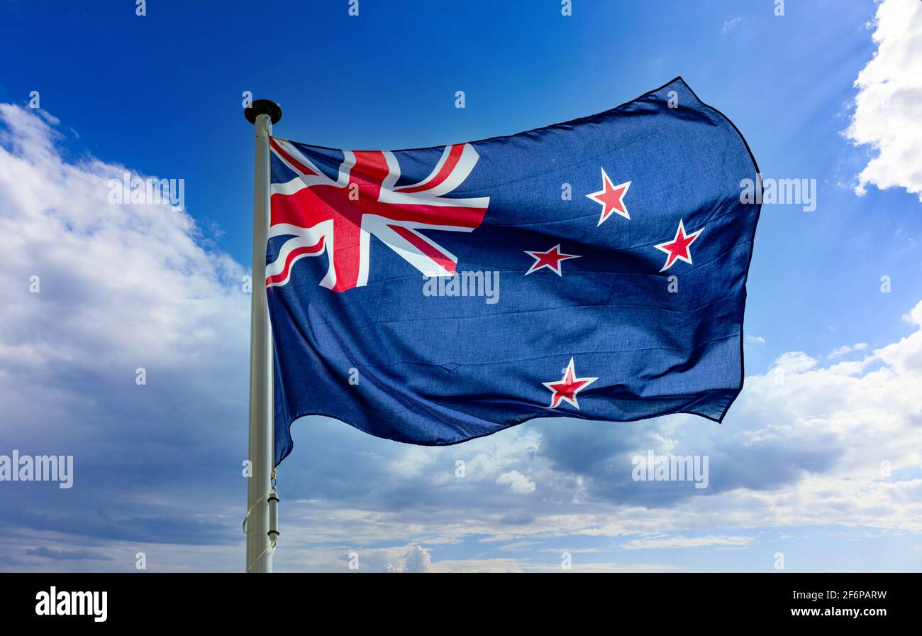Neuseeländische Flagge, NZ-Nationalsymbol auf einem Fahnenmast, der gegen den blau bewölkten Himmel winkt Stockfoto