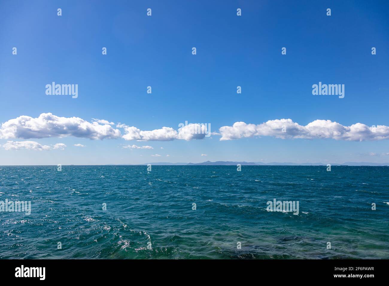 Blaues Meer und Himmel Hintergrund. Weiße Wolken am klaren Himmel über der Wasseroberfläche des Meeres, Ägäisches Mittelmeer, Urlaubsziel Griechenland. Stockfoto