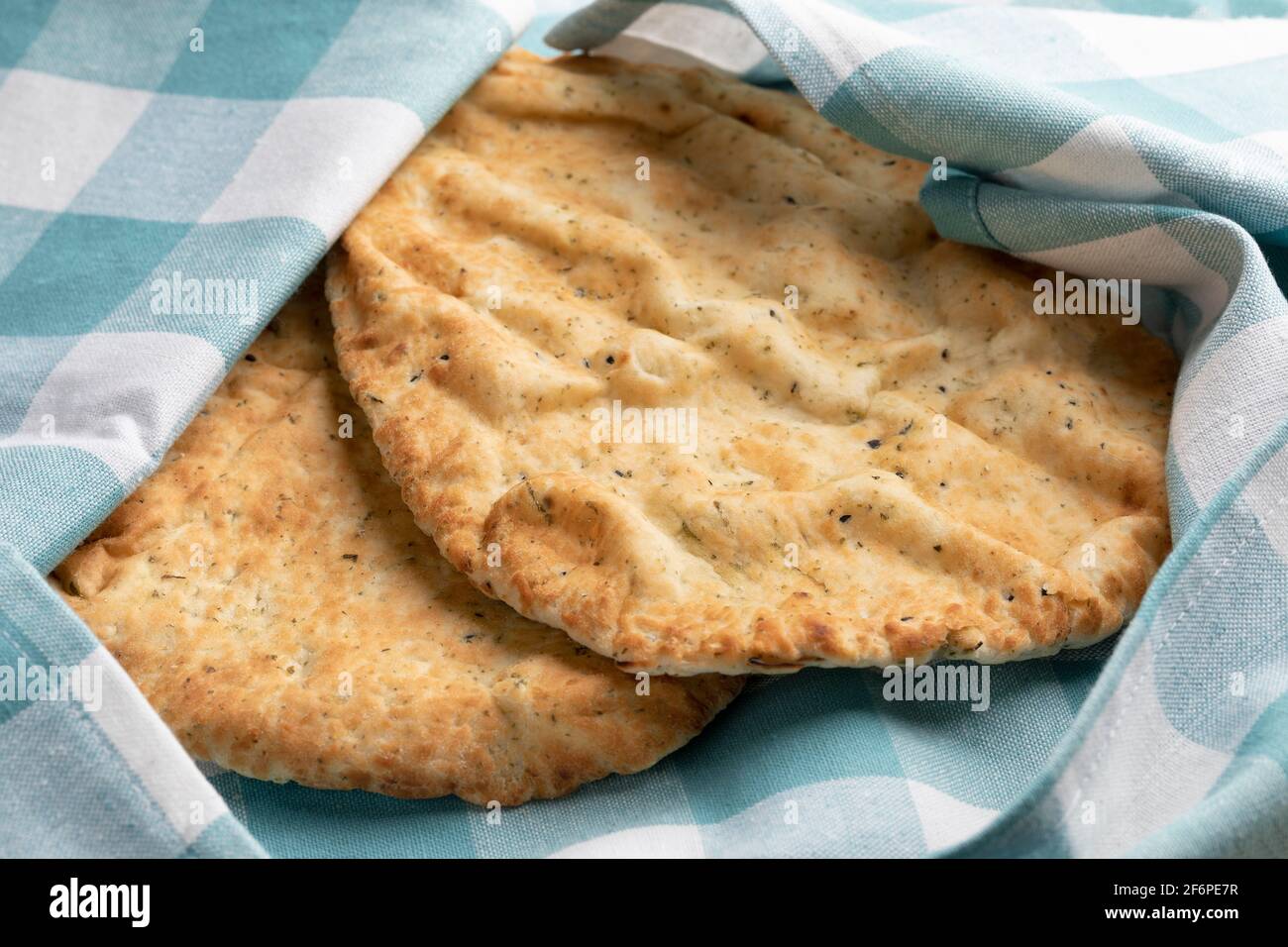 Frisch gebackenes Naan mit Knoblauch und Koriander in einem Tuch, um frisch aus der Nähe zu bleiben, Stockfoto