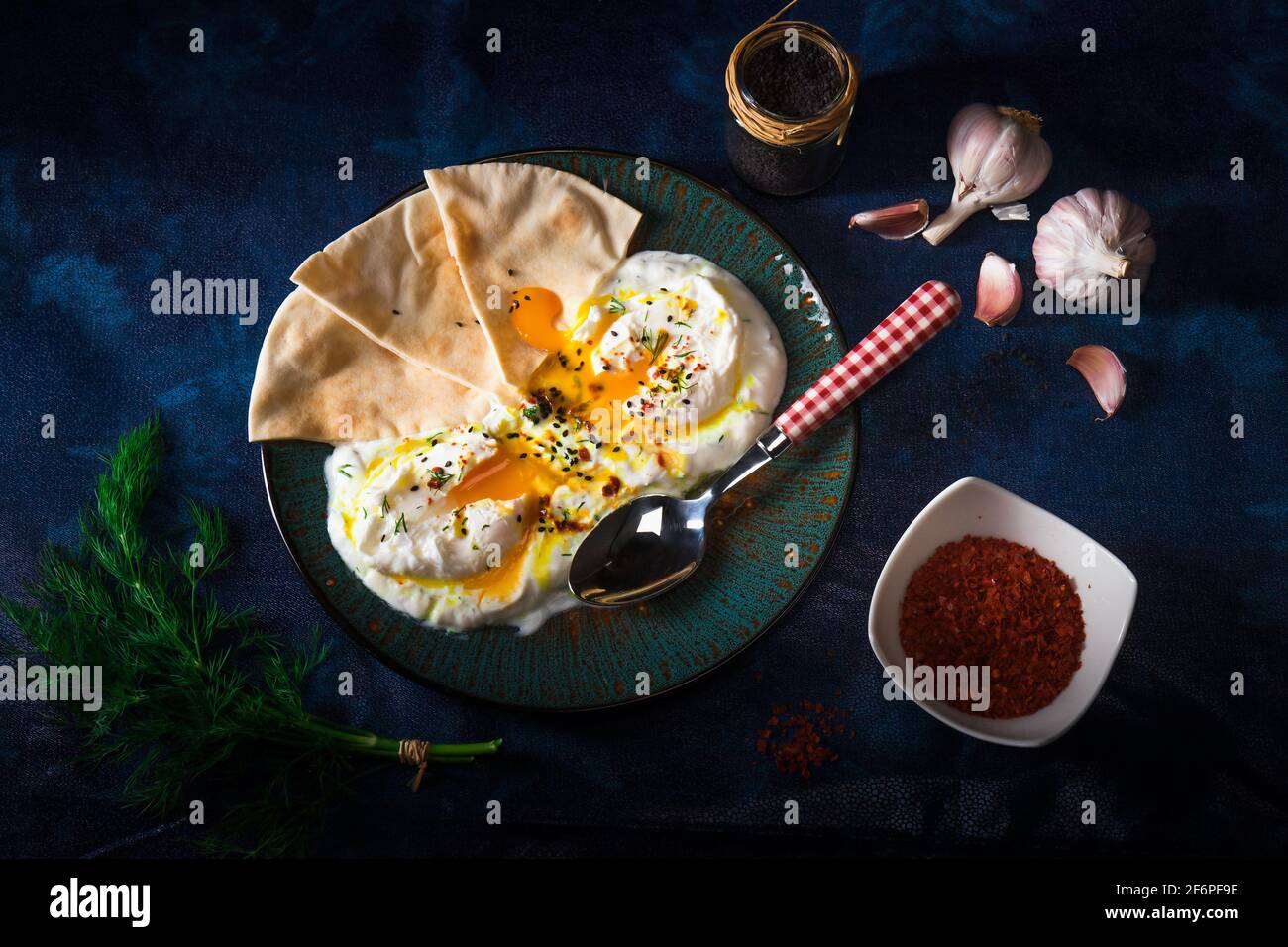 Schale mit Türkischen Cilbir Eier, Joghurt, pochierte Eier, Knoblauch, Chili, frischer Dill und zerlassener Butter. Verziert mit wenigen Stücke von lavash Brot ein Stockfoto