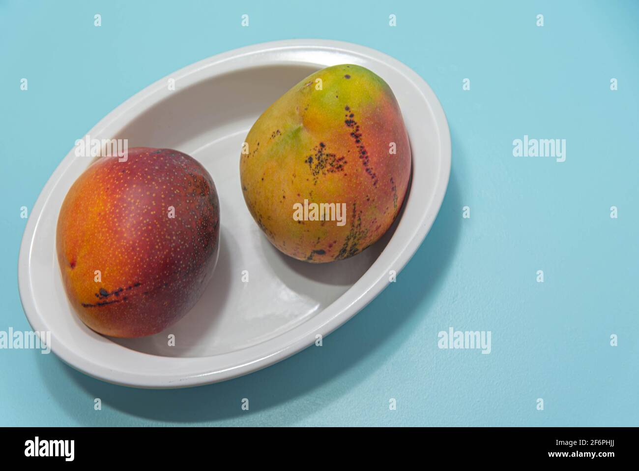 Frische rosa Mangofrucht auf blauem Hintergrund. Obst reich an Ballaststoffen und Protein-Quelle. Natürliche Nahrung und Entgiftung. Zutat für kulinarische Säfte und Sahne Stockfoto
