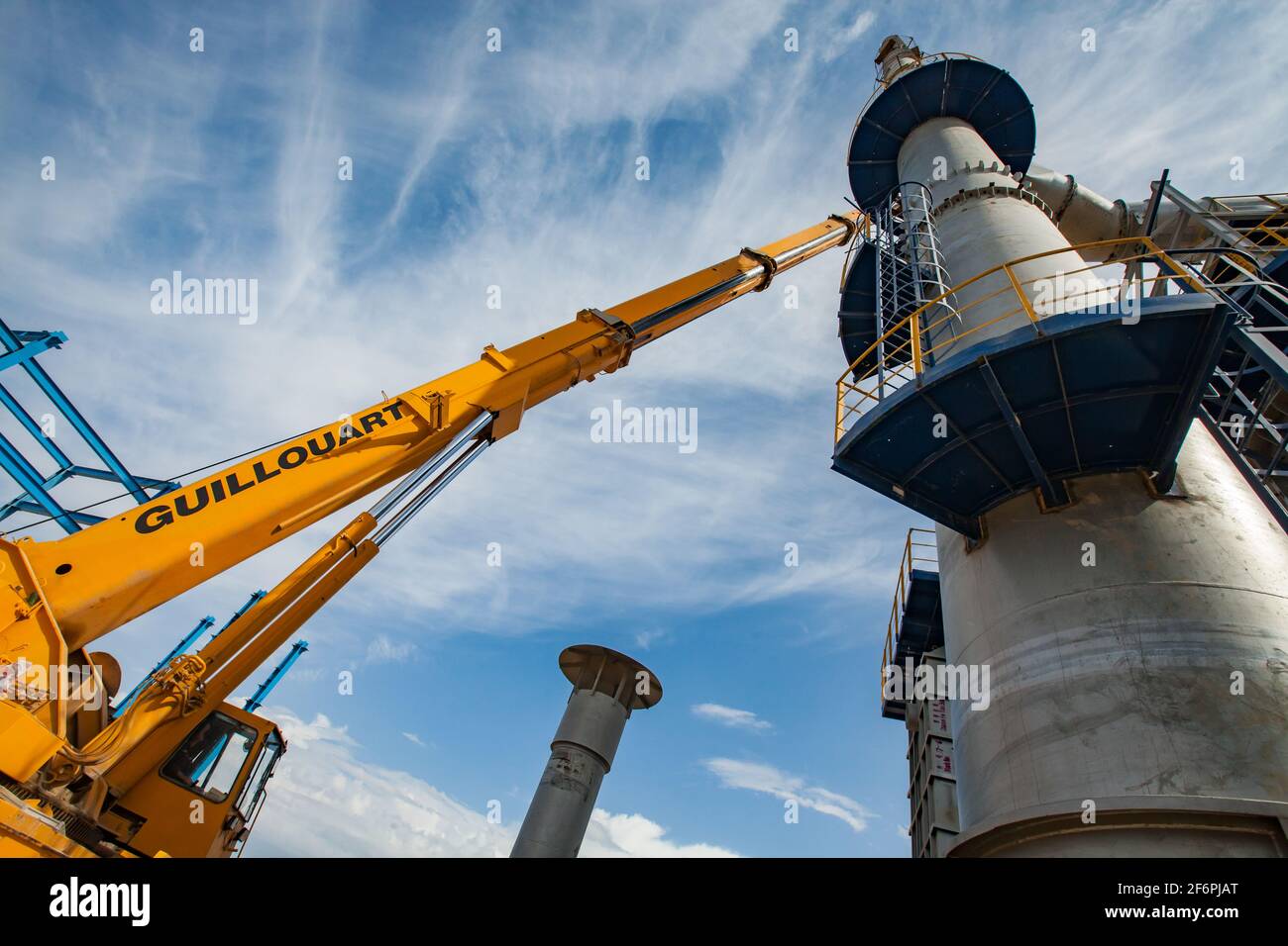 Aktau, Kasachstan - 19. Mai 2012 Bau einer asphaltischen Bitumenfabrik Raffineriesäule. Metalldestillationsturm und gelber hydraulischer Hebezeug. Blau sk Stockfoto