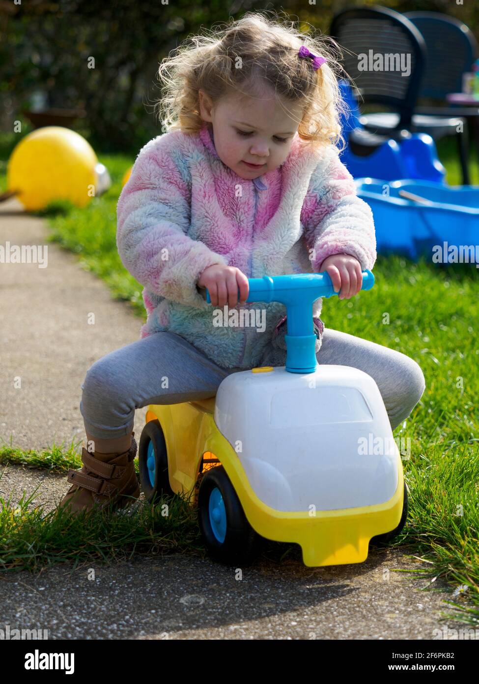 Kleinkind spielt auf einer Fahrt mit einem Spielzeugauto im Garten, Großbritannien Stockfoto