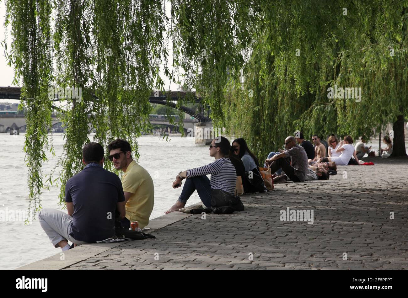 Junge Menschen an der Grenze zur seine in Paris, Frankreich. Pont des Arts im Hintergrund. Stockfoto