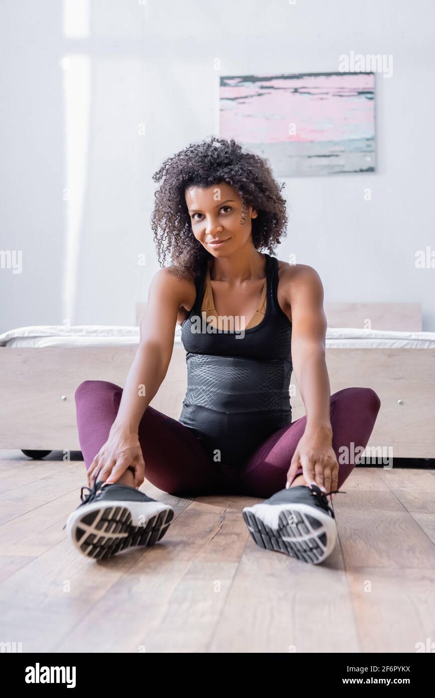 Schwanger afroamerikanische Frau in Sportkleidung sitzen auf dem Boden in Schlafzimmer Stockfoto