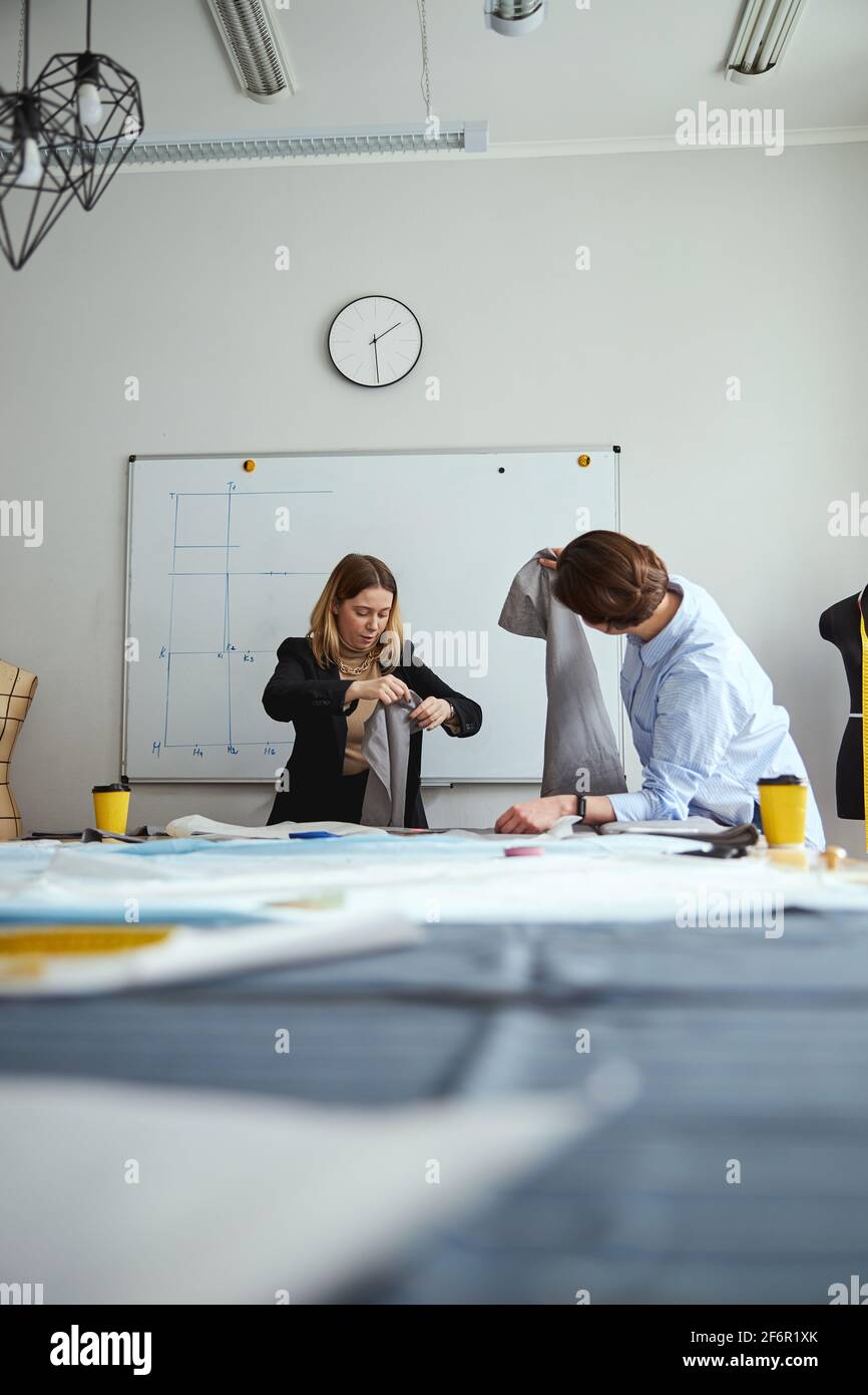 Lehrer und Schüler prüfen die Qualität des geschnittenen Stoffes Stockfoto