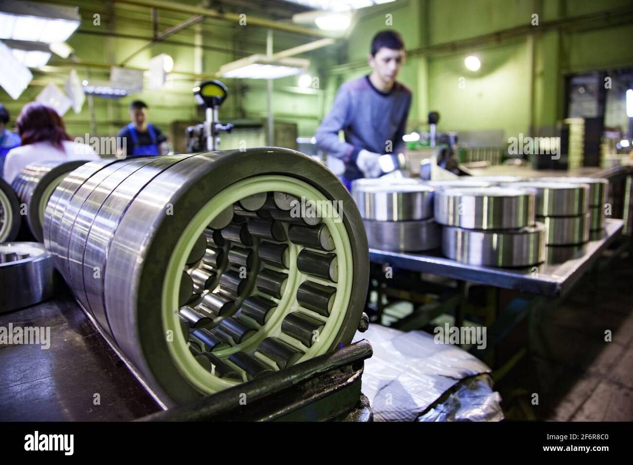 Stepnogorsk, Kasachstan: Lagerproduktionsanlage. Bereit-Wälzlager an der Qualitätskontrolllinie. Geringe Schärfentiefe, junger Arbeiter außer Fokus Stockfoto