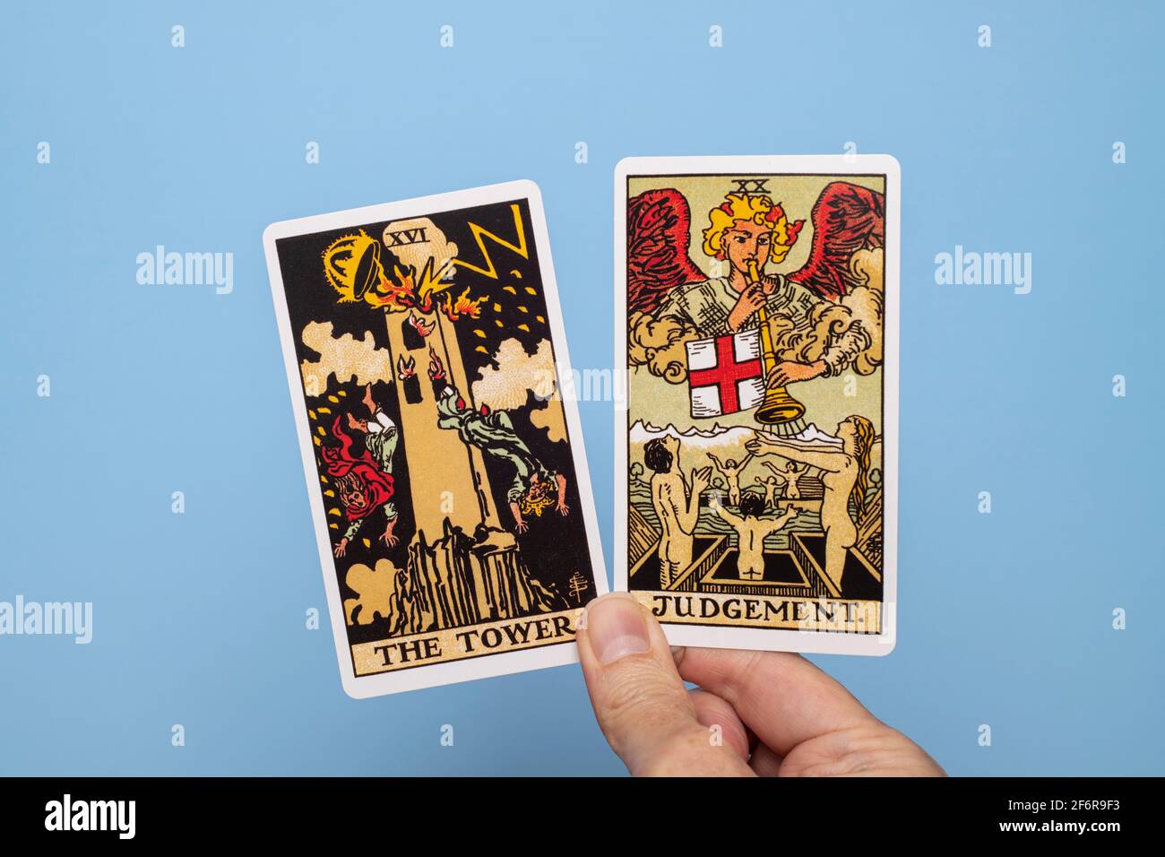 Hand hält zwei Tarot-Karten, den Turm und das Urteil. Stockfoto