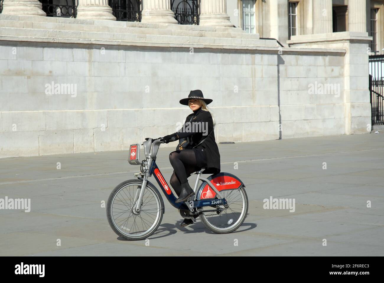 London, Großbritannien, 2. April 2021 stilvolle Frauenzylistin auf dem Santander Boris-Fahrrad überquert den Trafalgar Square. Am Karfreitag genießen die Menschen auf dem Trafalgar Square im West End Sonnenschein, da die Beschränkungen für die Sperrung durch das Coronavirus allmählich aufgehoben werden. Kredit: JOHNNY ARMSTEAD/Alamy Live Nachrichten Stockfoto